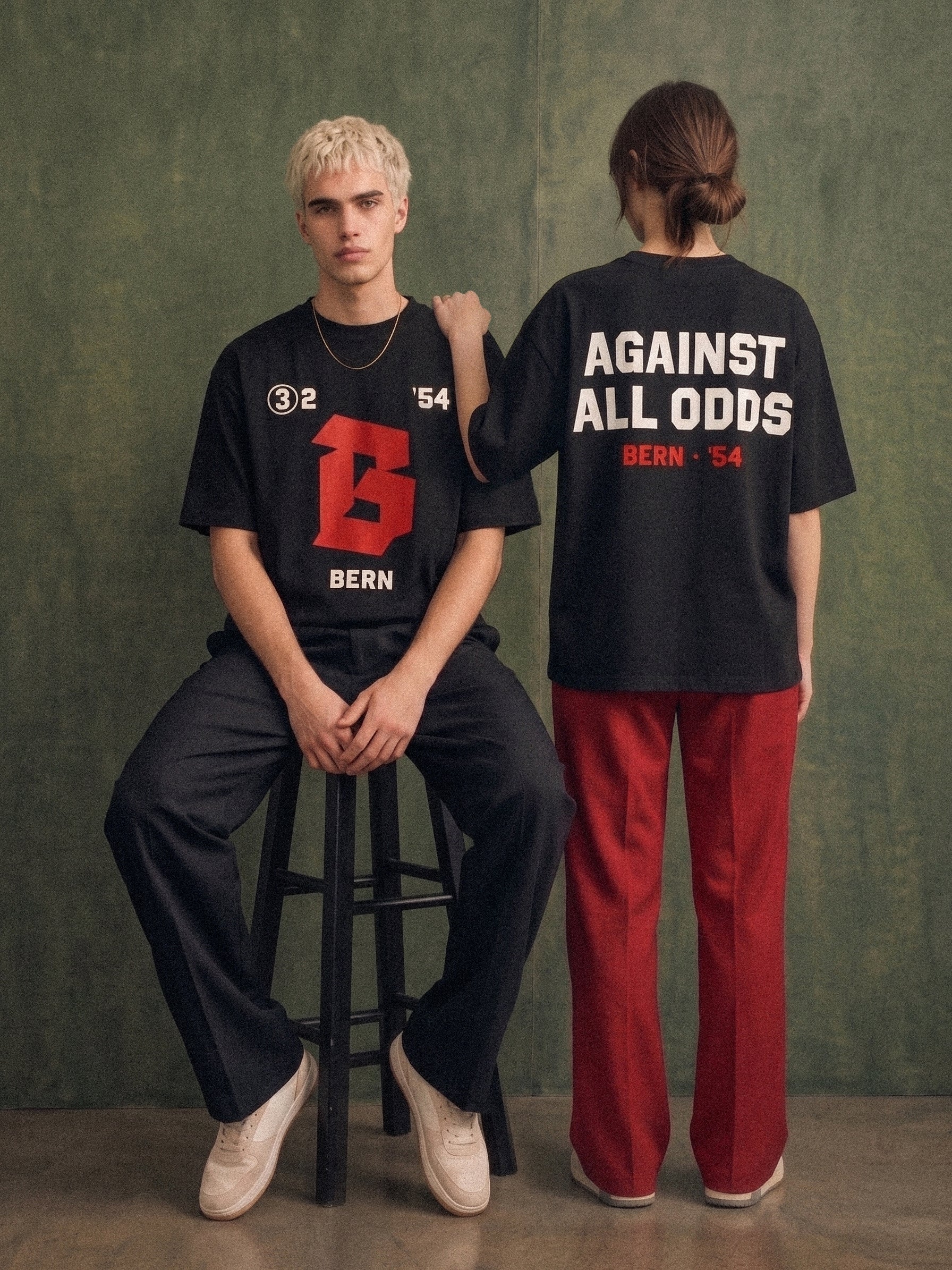Against All Odds tee, black, man and woman wearing oversized boxy fit showing 3:2 B Bern front print and Against All Odds Bern 54 back print, green studio lifestyle shot