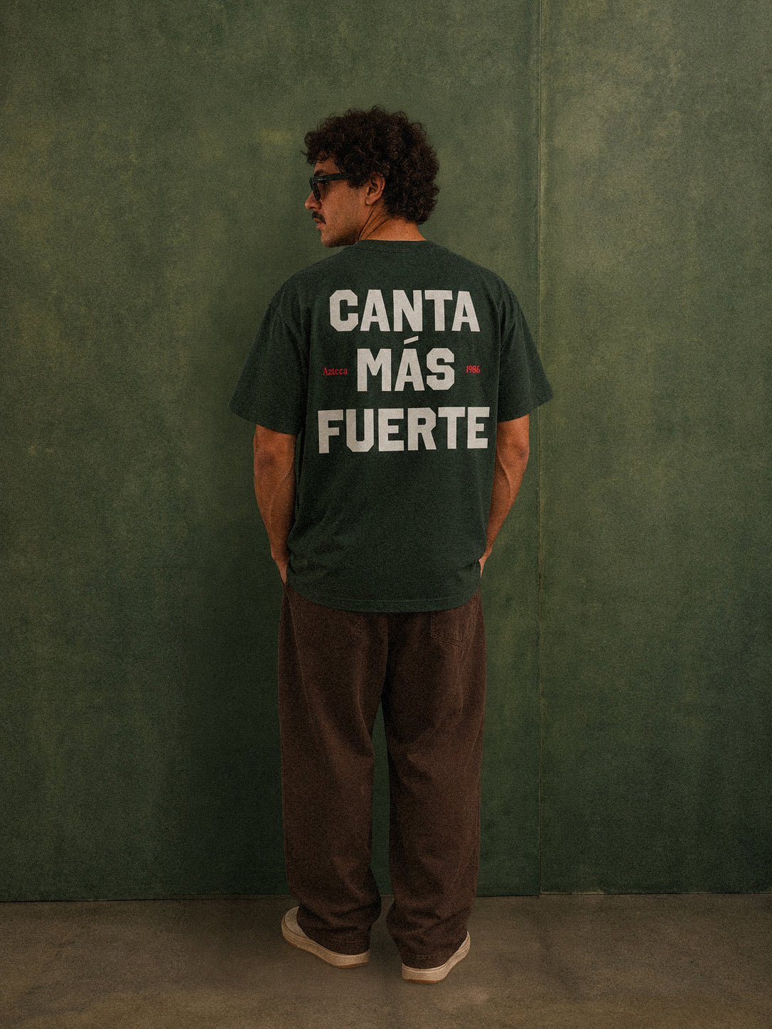 Mexico Azteca 12 tee, forest green, man wearing oversized fit showing Canta Más Fuerte back print, studio shot
