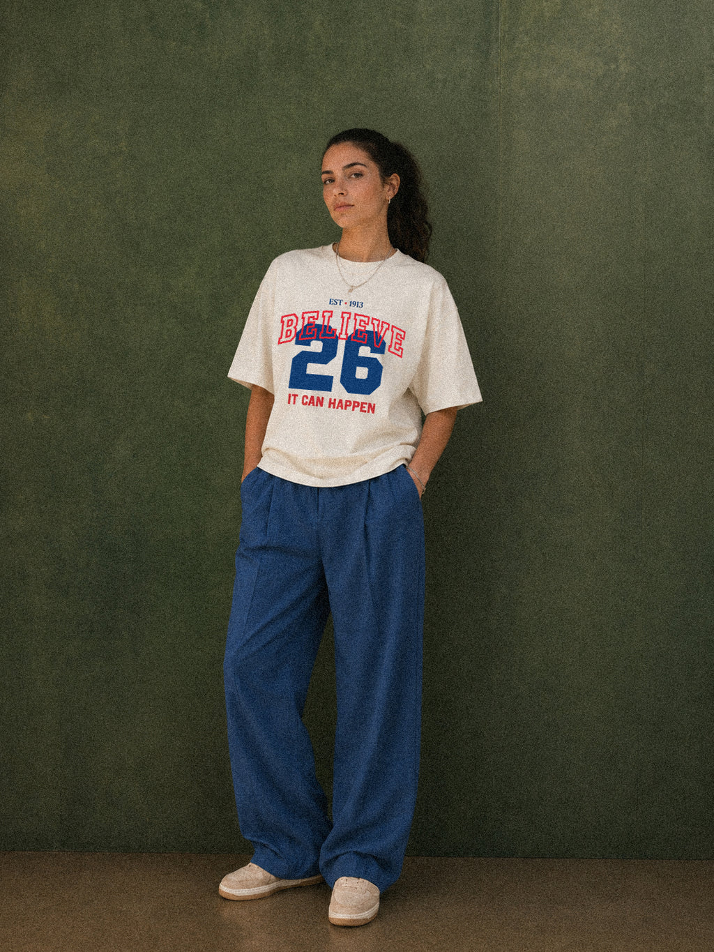 It Can Happen tee, cream, woman wearing oversized boxy fit showing Believe 26 It Can Happen front print in red and blue, green studio shot