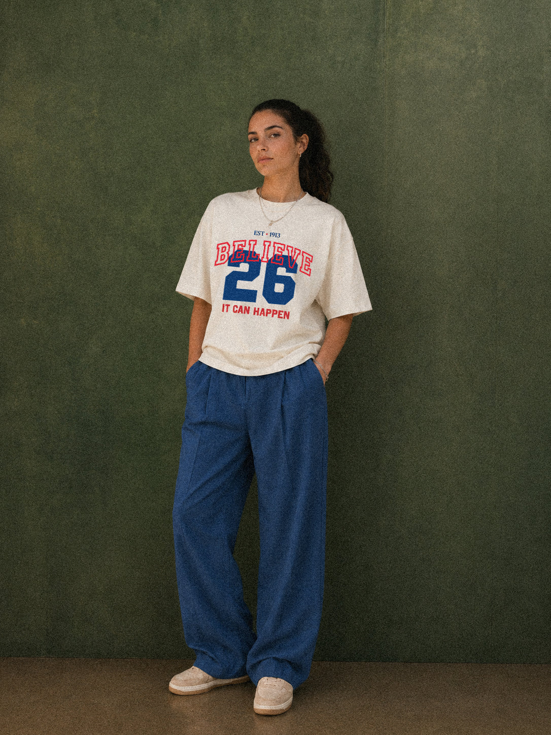 It Can Happen tee, cream, woman wearing oversized boxy fit showing Believe 26 It Can Happen front print in red and blue, green studio shot