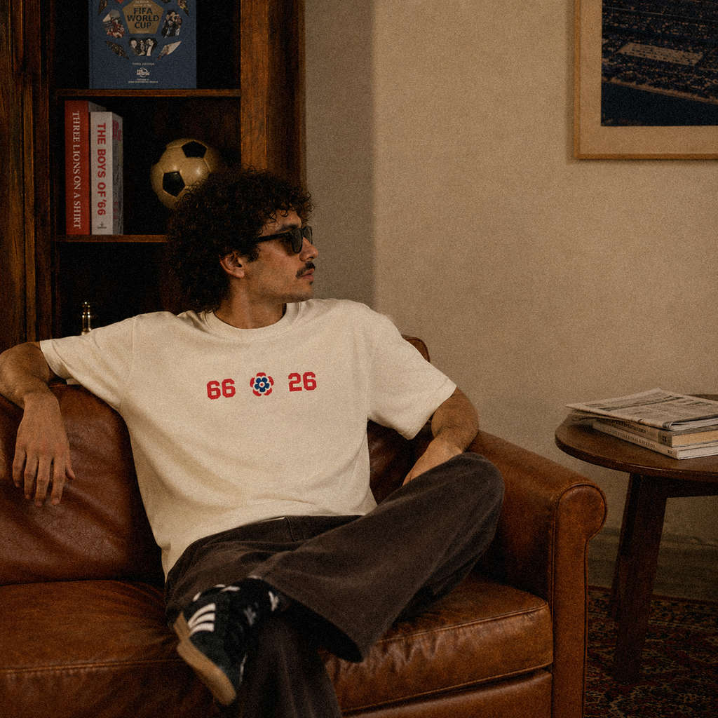 It's Coming tee, cream, man wearing oversized boxy fit showing 66 Three Lions 26 front print, indoor football room lifestyle shot