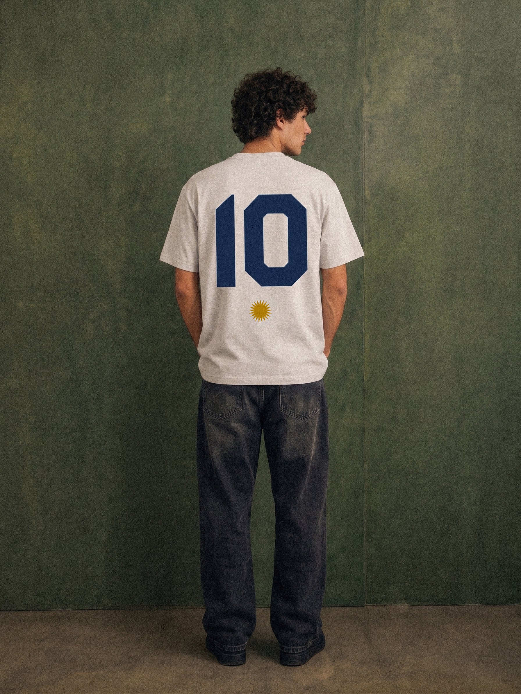 The Greatest Story tee, oat gray, man wearing oversized boxy fit showing Greatest Story Argentina back print, outdoor lifestyle shot